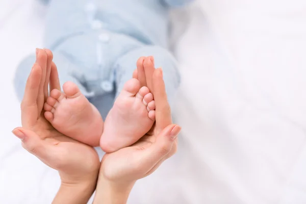 Moeder houden de voeten van haar baby-boys. — Stockfoto