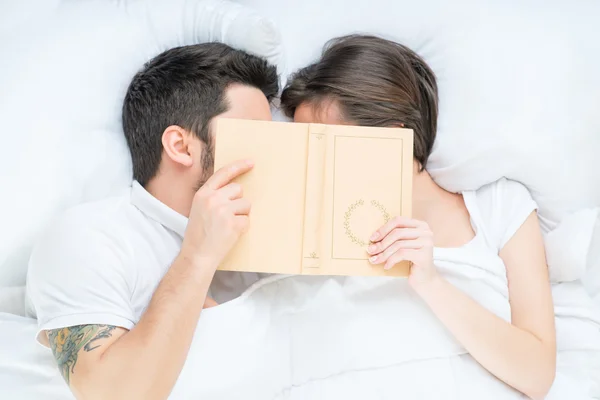 Пара прячет свои лица под книгой — стоковое фото