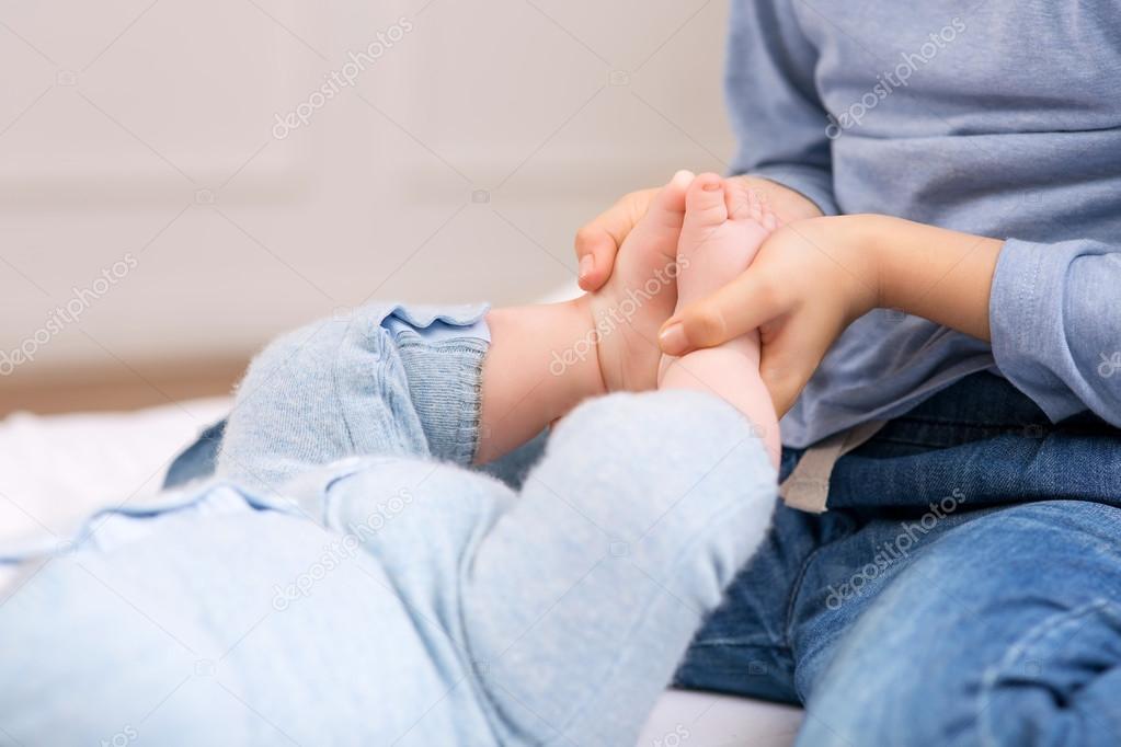 girl  holding her baby brothers tiny feet