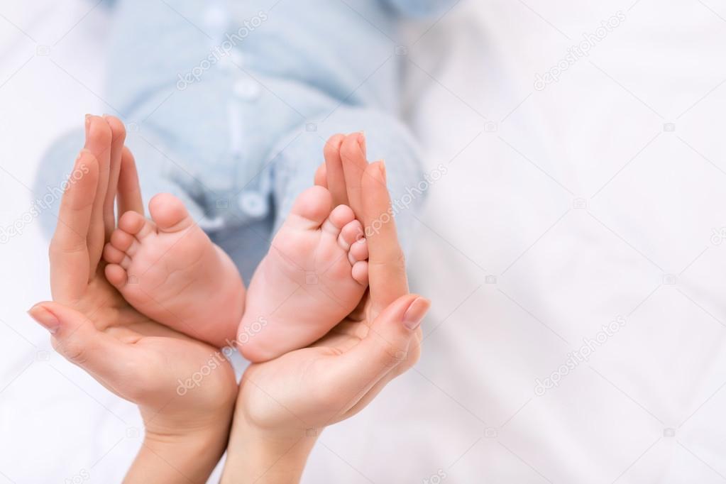 Mother holding her baby boys feet.
