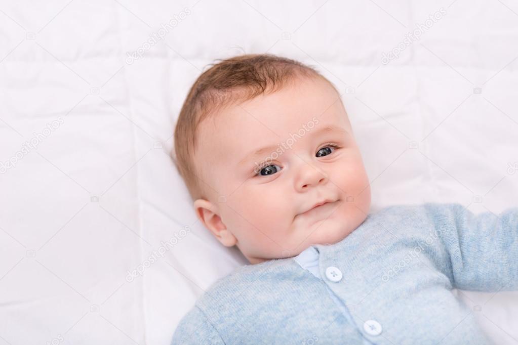Cute infant boy lying in bed.
