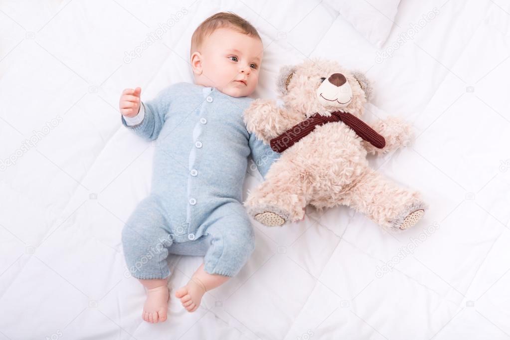 Infant boy  grabbing teddy bear.