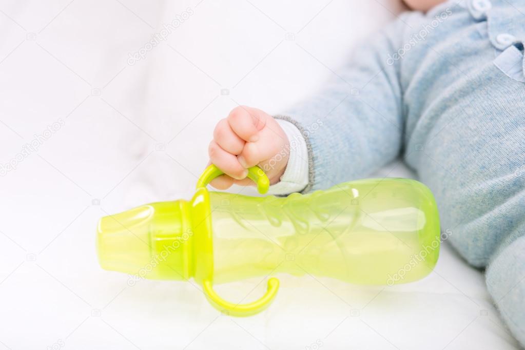 Infant boy grabbing a bottle.