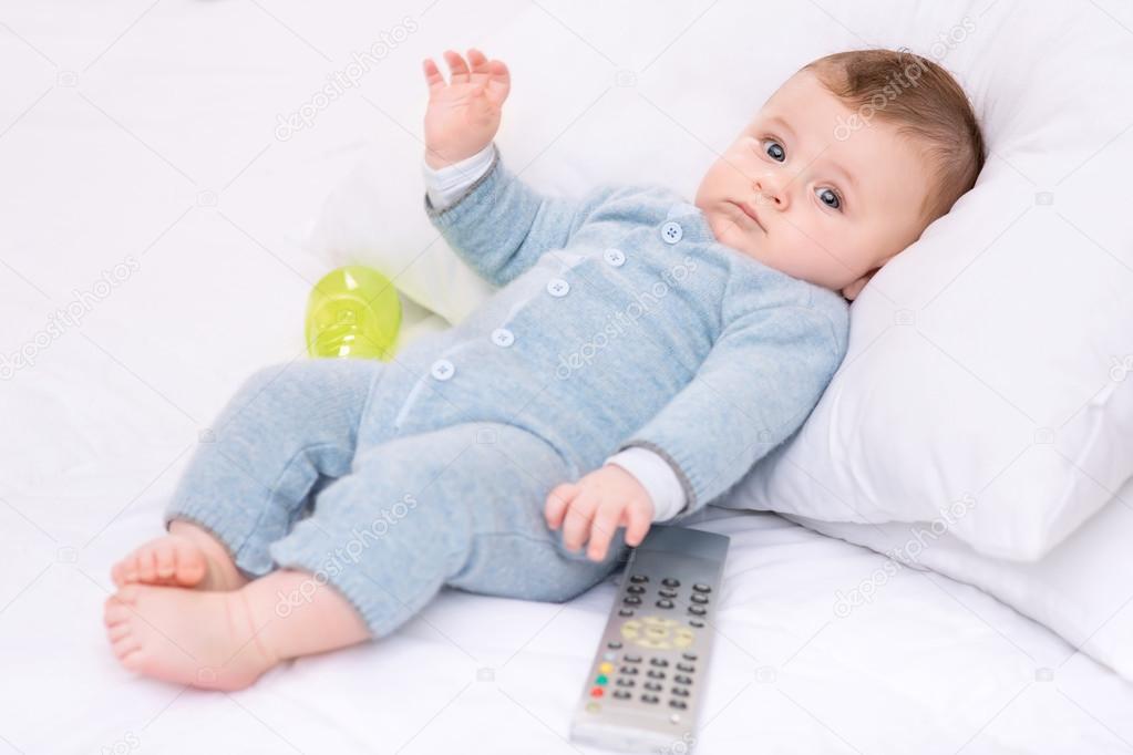 Infant boy with bottle and remote control.