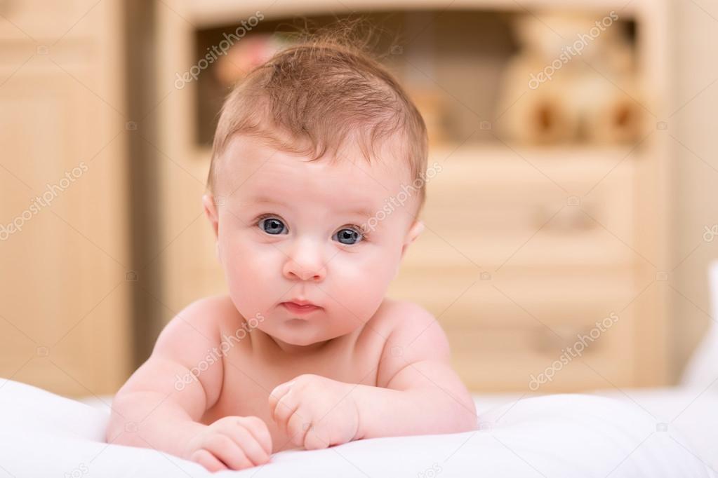 Infant child on bed in the room.