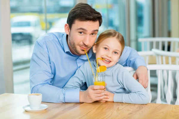 Hija compartiendo su jugo de naranja con el padre —  Fotos de Stock