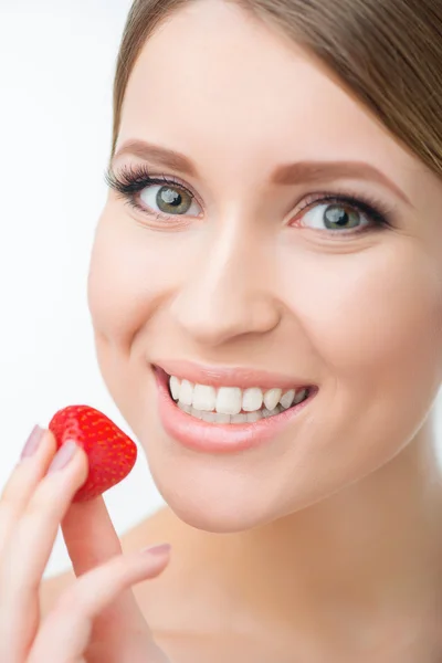 Hymyilevä nainen syö mansikkaa — kuvapankkivalokuva