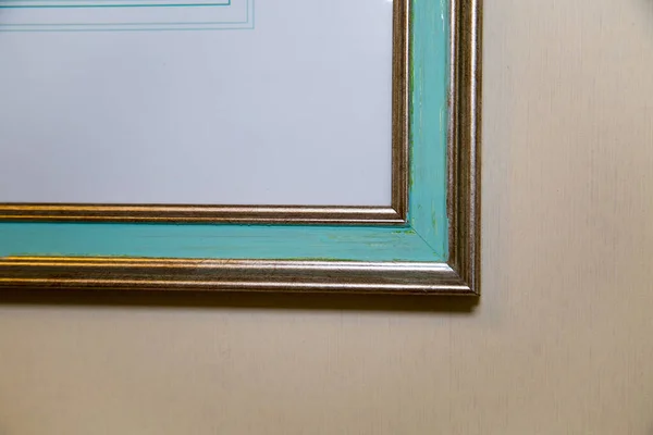 The corner of the frame is an artistic golden color with a stripe in the middle of a turquoise color on a gray wall. Backgrounds textures are an abstraction.