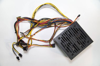 Çok renkli kabloları ve bağlantıları olan bilgisayar güç ünitesi beyaz bir arkaplanda izole edilmiş, ekipman onarımı modern teknolojiler..