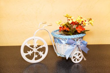 Dekoratif plastik üç tekerlekli bisiklet, güzel bir sepet, kahverengi bir rafta duran fiyonk ve çiçekler. Mağaza odasının iç tasarımı..