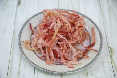 Kalamar talaşı (Lat. Yuvarlak bir tabakta, tahta bir masa arkaplanı var. Yiyecek bira için lezzetli bir atıştırmalıktır..