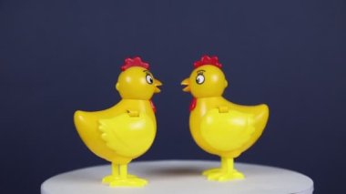Plastikten yapılmış parlak sarı tavukların figürleri koyu bir zemin üzerinde dönüyor. Mekanın kopyası olan tasarım konsepti, metin, gelenek ve nesneler eklemek..