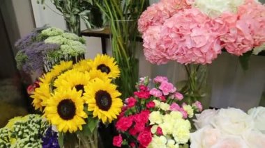 Zinyalar, güller, karanfiller ve beyaz arkaplandaki raflarda duran kırmızı beyaz pembe sarı renkli ayçiçeklerinden oluşan buketler. Flora ev çiçekleri..