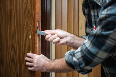 Yakın plan. Ahşap kapılı marangoz ahşap kapının kilidi için deliği hazırlar. İnşaat endüstrisi. 