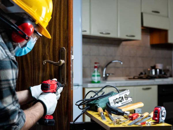 Carpenter worker at work repair and install a room door lock, wear the surgical mask to prevent Coronavirus infection. Preventing Pandemic Covid-19 at the workplace. Carpentry.