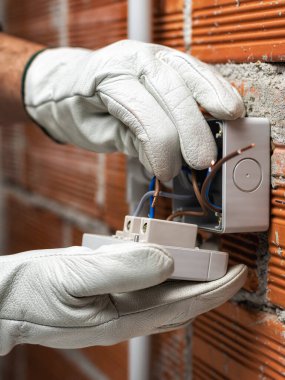 İşteki elektrik işçisi elektrik kablosunu konut elektrik sisteminin devre kesicisine yerleştiriyor. İnşaat endüstrisi.