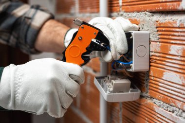 Elektrik işçisi tel sökücüyle birlikte çalışıyor. Konut elektrik sisteminin elektrik kablolarını hazırlıyor. İnşaat endüstrisi. 