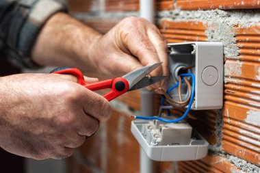 Makasla çalışan elektrik işçisi konut elektrik sisteminin elektrik kablolarını hazırlıyor. İnşaat endüstrisi.