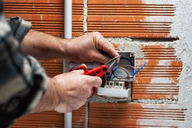 Makasla çalışan elektrik işçisi konut elektrik sisteminin elektrik kablolarını hazırlıyor. İnşaat endüstrisi.