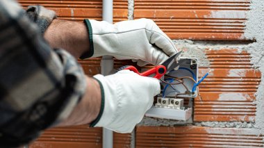 Makasla çalışan elektrik işçisi konut elektrik sisteminin elektrik kablolarını hazırlıyor. Koruyucu eldivenlerle güvenli bir şekilde çalışmak. İnşaat endüstrisi.