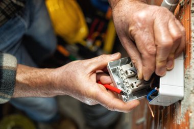 Üst Manzara. İşteki elektrik işçisi elektrik kablosunu konut elektrik sisteminin devre kesicisine yerleştiriyor. İnşaat endüstrisi.