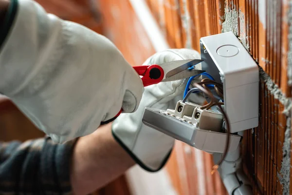 Bottom view. Electrician worker at work with scissors prepares the electrical cables of an electrical system. Working safely with protective gloves. Construction industry.