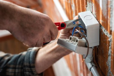 Alt manzara. Makasla çalışan elektrik işçisi elektrik sisteminin elektrik kablolarını hazırlıyor. İnşaat endüstrisi.