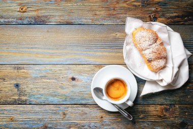 Yukarıdan bak. Açık mavi ahşap arka planda bir fincan sıcak İtalyan espresso kahvesi ve kruvasan. Yiyecek ve içecek. Yaşam biçimi.