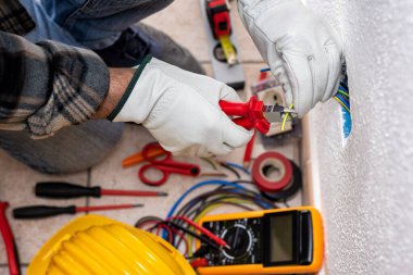 Üst Manzara. Kablo kesiciyle çalışan elektrik işçisi bir elektrik sisteminin elektrik kablolarını hazırlıyor. Koruyucu eldivenlerle güvenli bir şekilde çalışmak. İnşaat endüstrisi.