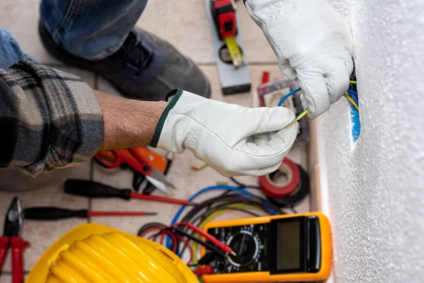 上から見る 作業中の電気作業員は電気システムの電気ケーブルを準備します 保護手袋で安全に作業します 建設業 — ストック写真