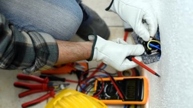 Üst Manzara. Tornavidayla çalışan elektrik işçisi elektrik sisteminin prizlerindeki elektrik kablolarını tamir ediyor. Koruyucu eldivenlerle güvenli bir şekilde çalışmak. İnşaat endüstrisi. Görüntü.