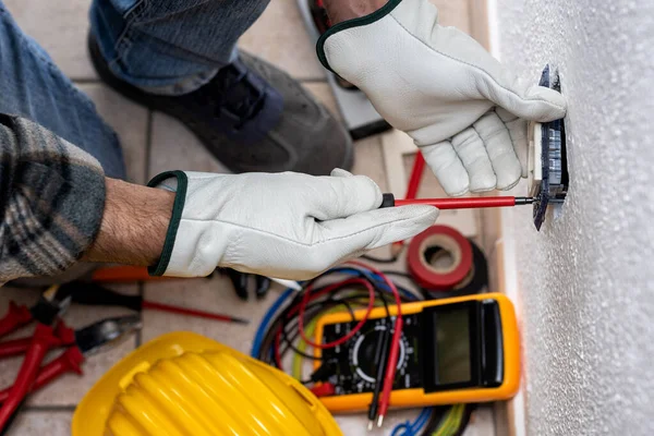 Top view. Electrician worker at work installs the electric socket of a residential electrical system. Working safely with protective gloves. Construction industry.