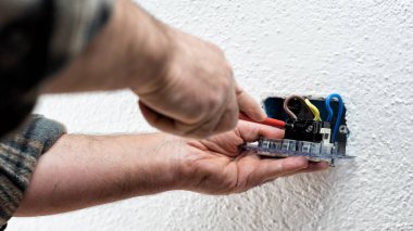 Tornavidayla çalışan elektrik işçisi elektrik sisteminin prizlerindeki elektrik kablolarını tamir ediyor. İnşaat endüstrisi.