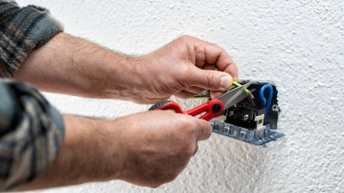 Makasla çalışan elektrik işçisi elektrik sisteminin elektrik kablolarını hazırlıyor. İnşaat endüstrisi.