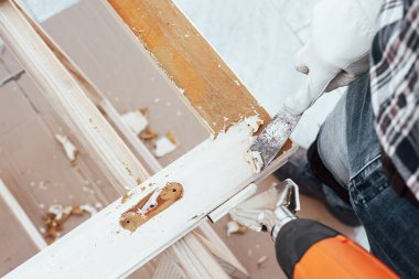 Marangoz ısı tabancası ve odun kazıyıcı kullanarak eski ahşap penceredeki boyayı temizler. İnşaat endüstrisi, marangozluk. Yenileme.