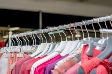 Giysiler bir mağazanın rafında asılı. 