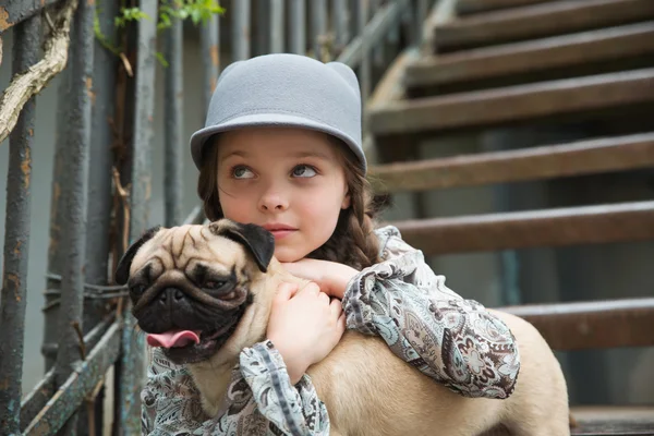 Little girl playing with her pug dog outdoors in rural areas — Stock Photo, Image