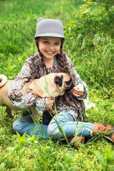 Liten flicka leker med sin mops hund utomhus i landsbygdsområden — Stockfoto