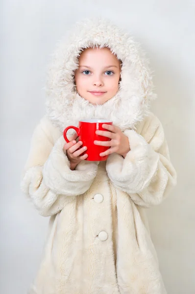 Menina sorridente em roupas de inverno com uma xícara vermelha de drin quente — Fotografia de Stock