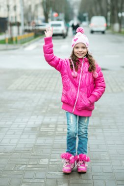 Şehirde yürüyen ping ceketli küçük bir kız. Gülümseyen chi