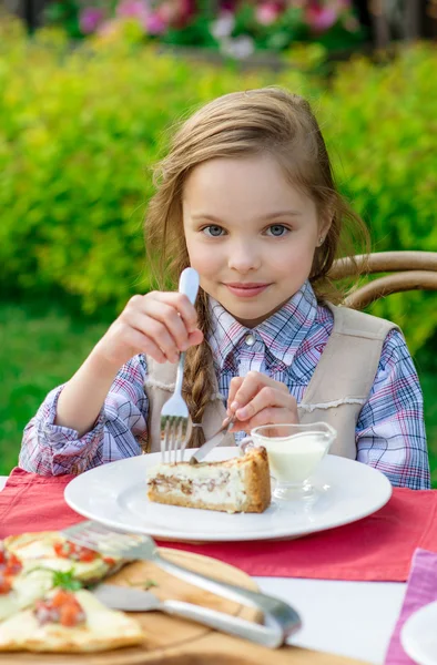 Niedliches kleines Mädchen sitzt am Esstisch und isst — Stockfoto