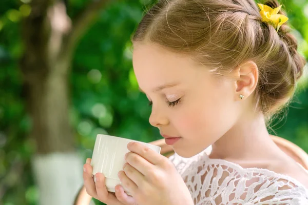 Liten flicka med vit kopp utomhus. — Stockfoto
