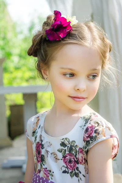 Mała dziewczynka w kolorowej sukni i kwiatach. — Zdjęcie stockowe