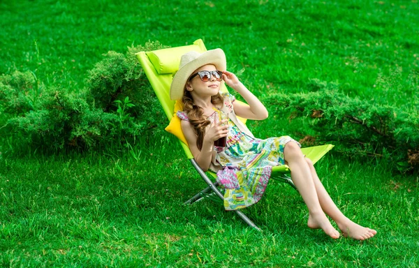 Милая девушка расслабляется с соком на стуле на траве . — стоковое фото