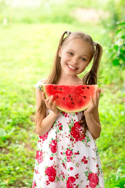Lächelndes kleines Mädchen mit blauen Augen isst eine Scheibe Wassermelone — Stockfoto