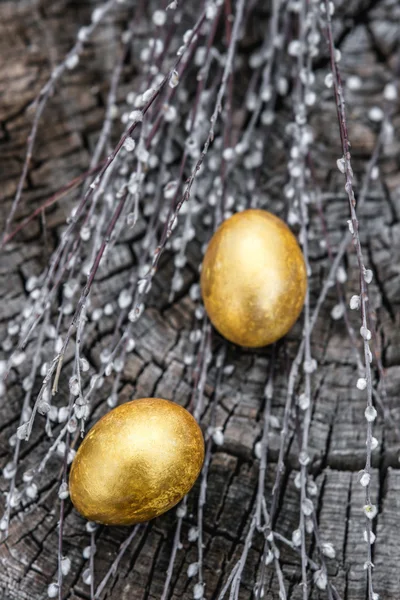 Œufs de Pâques dorés sur fond en bois avec des brindilles de saule. Plat — Photo