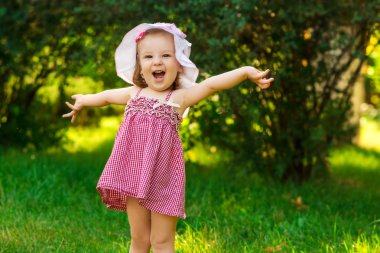 Parkta bir çayırda gülümseyen küçük kız. 