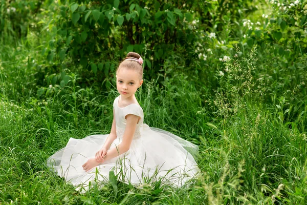 Gadis kecil yang cantik dengan gaun putih berpose di rumput — Stok Foto