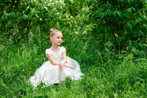 Linda menina em um vestido branco posando na grama — Fotografia de Stock