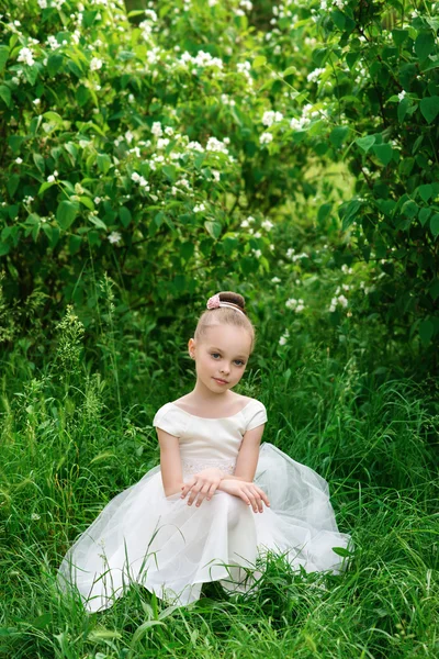 Linda menina em um vestido branco posando na grama — Fotografia de Stock